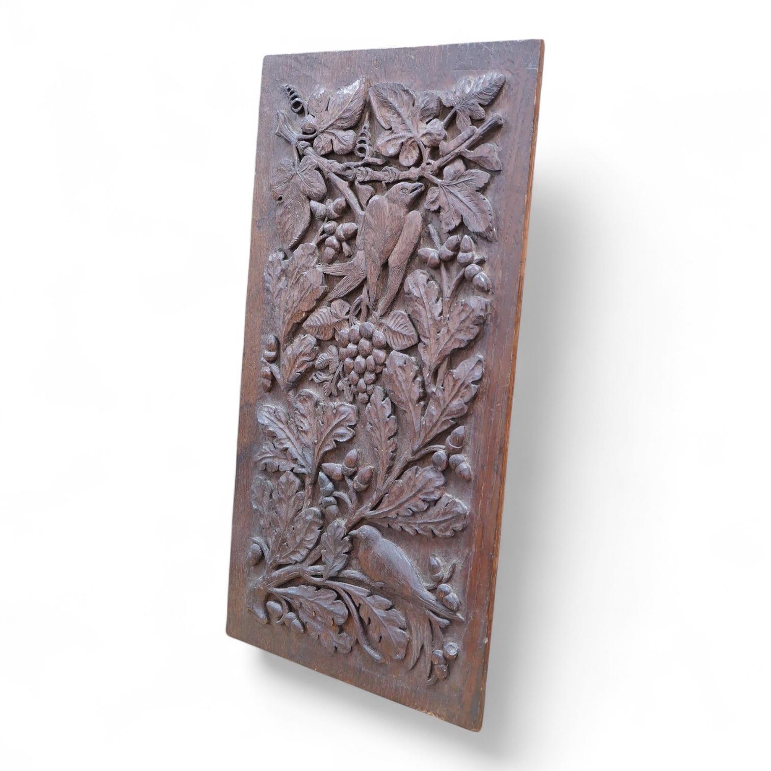 A carved oak relief panel, of acorns, oak leaves and a bird, 64cm high, 33cm deep